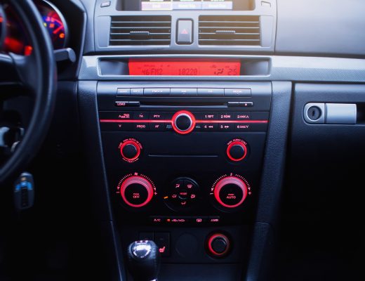 A radio and air conditioning system with red buttons in a modern car panel. The AC unit will keep you cool during the summer.