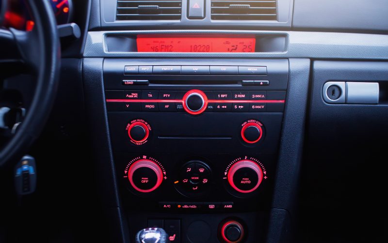 A radio and air conditioning system with red buttons in a modern car panel. The AC unit will keep you cool during the summer.