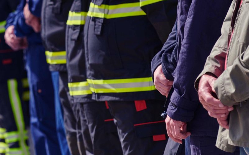 A line of first responders with their hands folded in front of them. There are fire and medical responders.