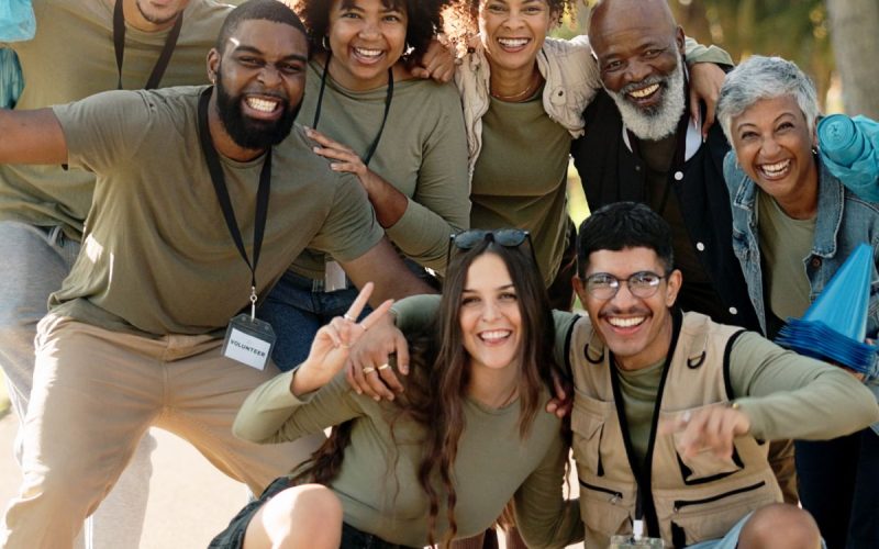 A group of volunteers wearing coordinated green clothes, standing together in a communal area and smiling.