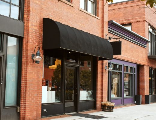 A close-up of a strip of charming brick mom and pop shops that are aligned along the block of a small town.