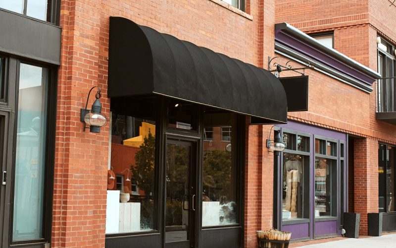 A close-up of a strip of charming brick mom and pop shops that are aligned along the block of a small town.