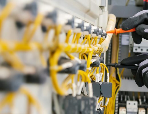 Close-up of an electrical engineer testing electrical wiring on protective relays with a multimeter.
