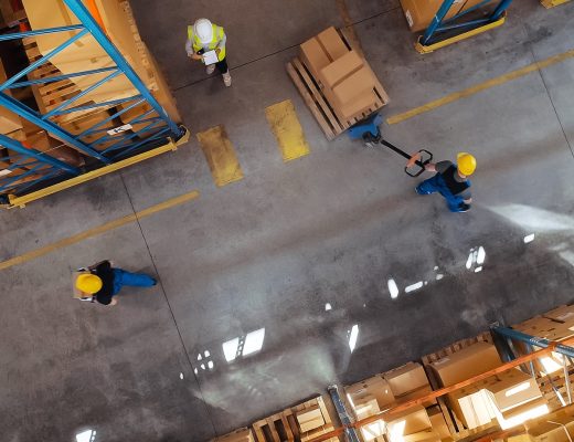An arial view of a warehouse floor, there are several people around the area. One person is pulling a dolly.