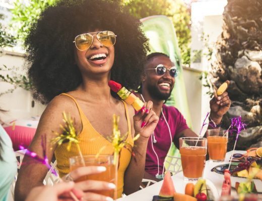 A diverse group of friends having fun at a backyard home party. They're eating fruit and drinking cocktails.