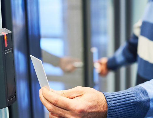 A person wearing a striped blue and white sweater is holding a white key card up to a black card reader.
