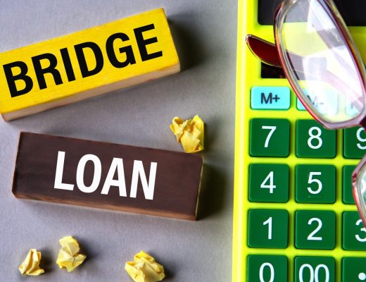 a yellow "Bridge" block and a brown "Loan" block lying beside crumpled paper, a green calculator, and eyeglasses.