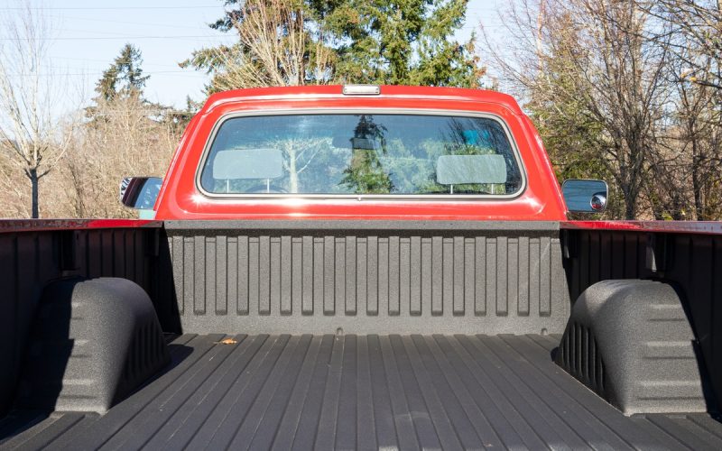 The back of a red turbo diesel truck with the trunk bed open. The truck bed is empty and clean with trees in the background.