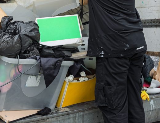  Person loads mixed household waste, cardboard boxes, and storage bins into a truck for bulk junk removal.